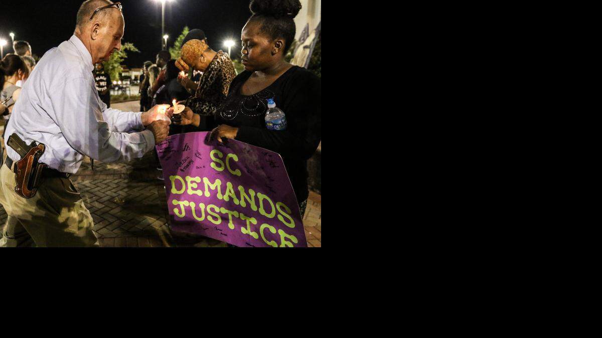 
Charleston County Sheriff Al Cannon lights a candle at a rally for Walker Scott in front of the North Charleston City Hall on Wednesday night. 

