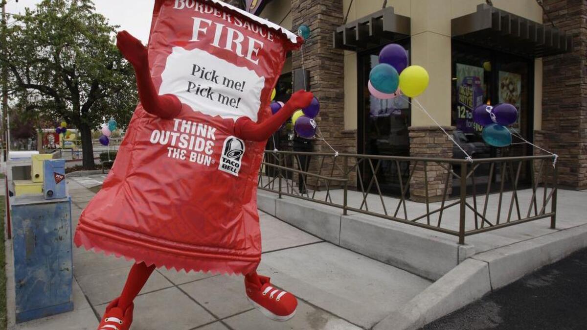 File photo. This Dec. 13, 2010 photo shows a Taco Bell restaurant opening with a person in a taco sauce outfit outside in Mountain View, Calif.