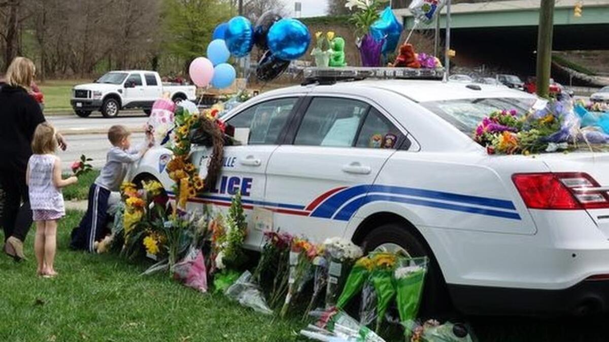 A young boy and his family leave flowers and a card in memory of Officer Allen Jacobs Saturday.