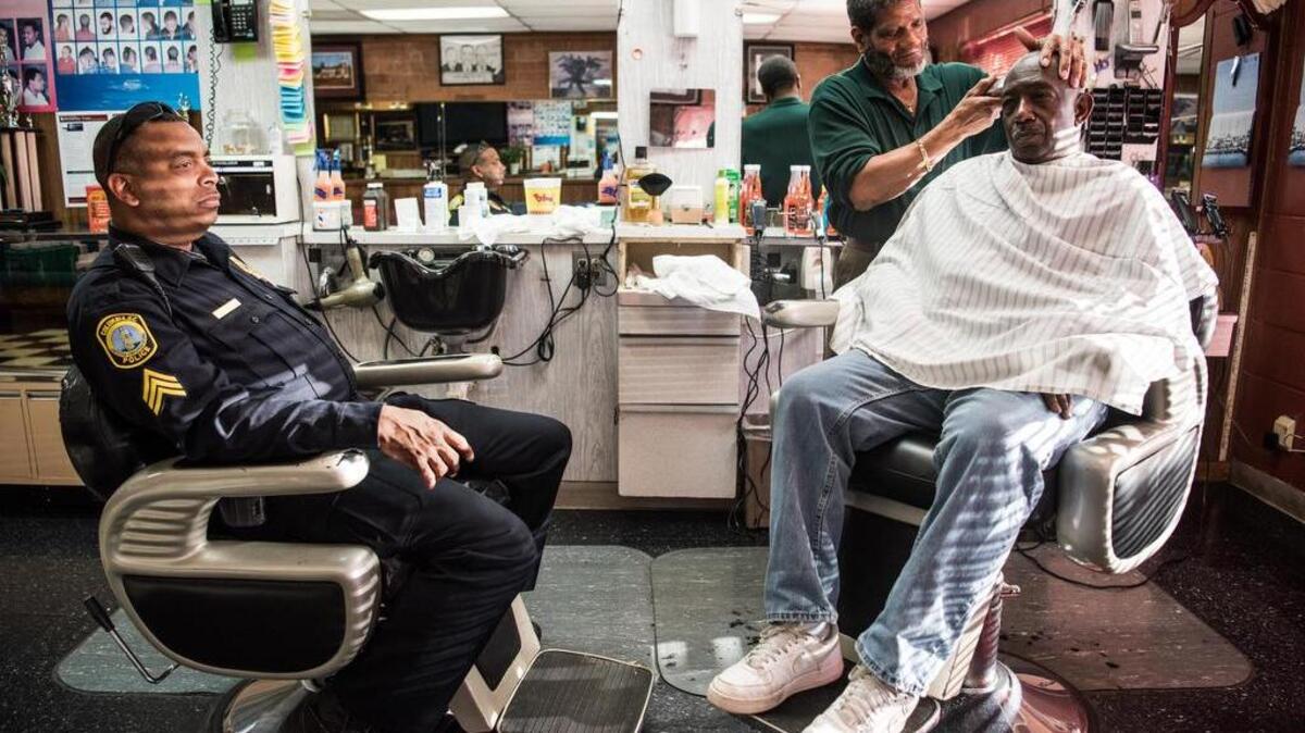 Johnny Cole gives a hair cut to Davis Redden, right, as Columbia Police Sgt. Darring Hicks, left, waits for his turn at Cole's Barber Shop on Friday.