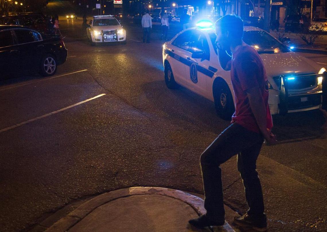 A bystander talks on his phone as Columbia Police Department officers investigate a situation in front of Lucky’s. Officers respond to calls varying from assault to theft on any given night.
