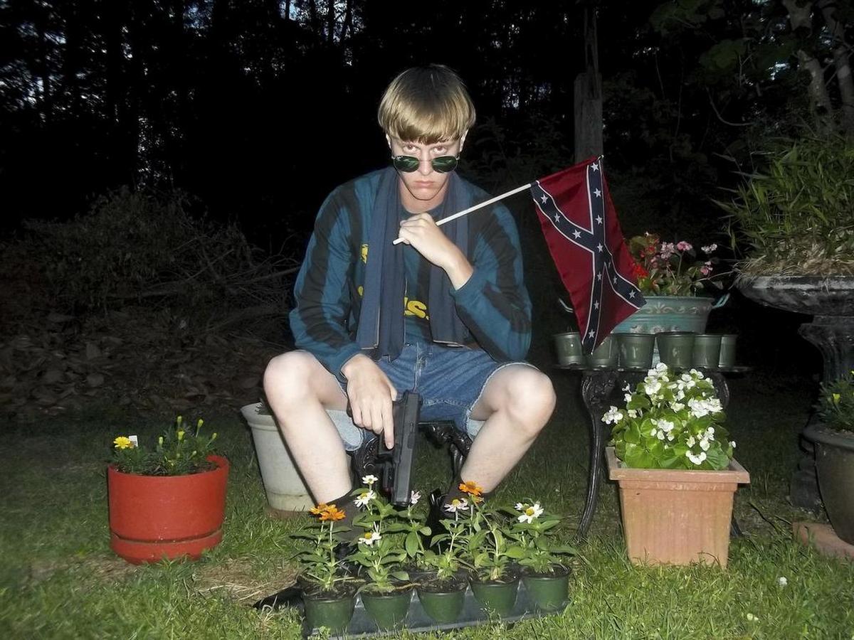 Dylann Roof posing for a photo holding a Confederate flag.