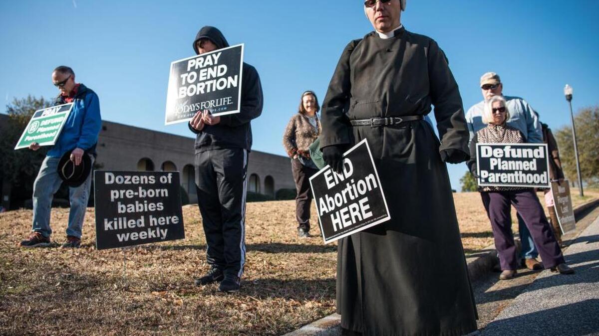 Paul Sterne joins in prayer with demonstrators protesting at an anti-Planned Parenthood rally at the Columbia Health Center on Saturday.