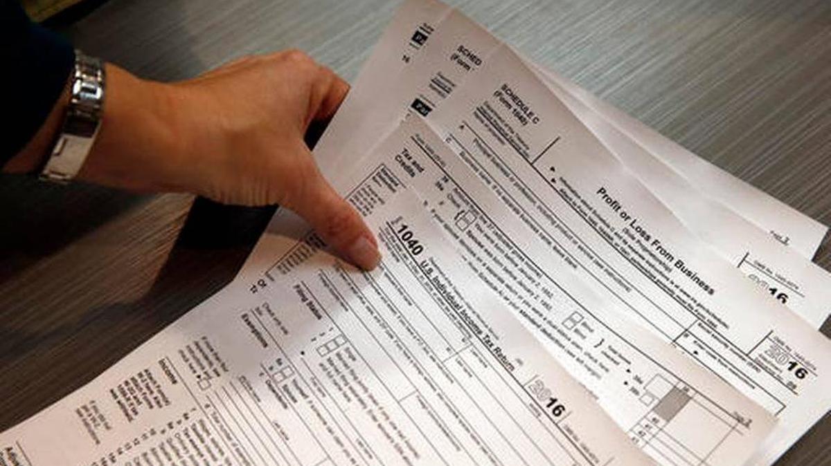 In this Jan. 14, 2017, photo, tax professional and tax preparation firm owner Alicia Utley reaches for hard copies of tax forms while working to stay caught up on a Saturday at the start of the tax season rush, in her offices at Infinite Tax Solutions, in Boulder, Colo. The IRS will begin accepting returns on Jan. 23, and tax experts recommend that Americans continue to file their returns early.