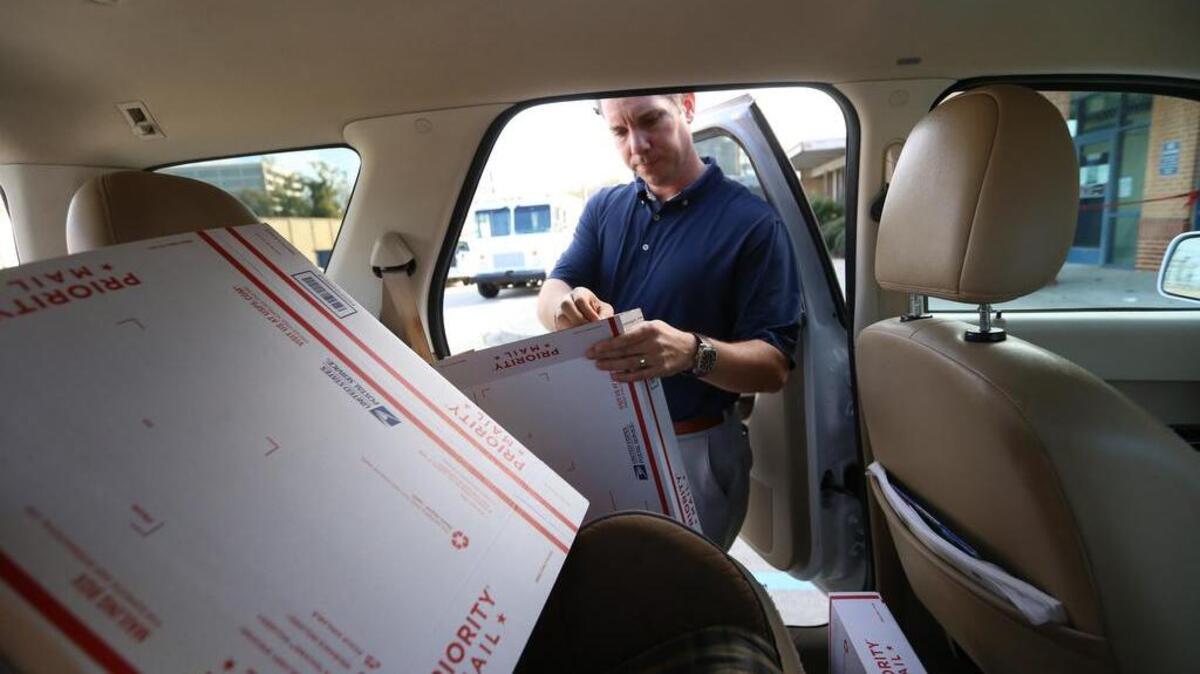 Shawn Skillman packages Christmas gifts in his car outside the Five Points post office, which is operating out of a truck behind him because of flood damage.