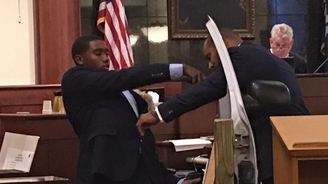 Kierin Dennis, left, on Monday re-enacts how he stabbed a Dutch Fork High School student in 2014. His lawyer Todd Rutherford, center, plays the role of victim Da’Von Capers. Judge Eugene Griffith, background, is presiding over the murder trial in Lexington County.
