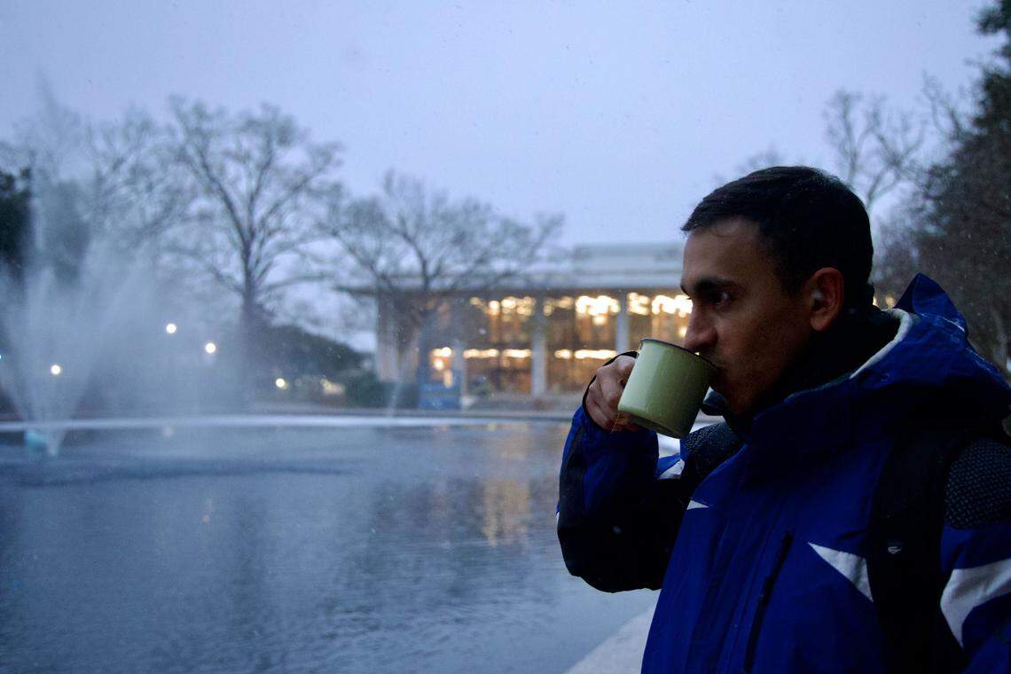 Ademar Fernandez, a geophysics PhD student at the University of South Carolina, has tea with and pineapple cake on campus as it snows on Jan. 21, 2025. Fernandez is from southern Chile, a polar climate, and missed seeing snow.