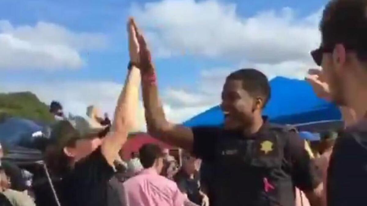 Richland County Deputy K. Scott exchanges high-fives with USC fans after making a shot in their beer pong game while patrolling the Morrison Memorial Lot before the Vanderbilt game.