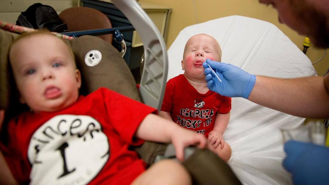 Kilian Daugherty, 1, gets his nose cavity swabbed for the flu by emergency department technician Jake Weatherford as his sister Madison, left, waits to be examined as well for flu symptoms at Upson Regional Medical Center in Thomaston, Ga., Friday, Feb. 9, 2018. The flu has further tightened its grip on the U.S. This season is now as bad as the swine flu epidemic nine years ago. A government report out Friday shows 1 of every 13 visits to the doctor last week was for fever, cough and other symptoms of the flu. That ties the highest level seen in the U.S. during swine flu in 2009.