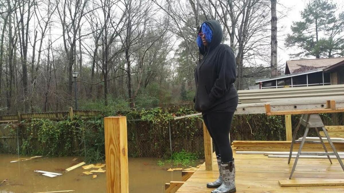 Shafeka Carter looks over the flood in the backyard of her home in the Pine Glen neighborhood in St. Andrews created when the lower Saluda River overflowed after water was released from Lake Murray upstream.