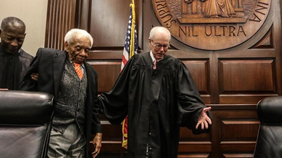 Chief Justice Costa M. Pleicones and Justice Donald Beatty help former Chief Justice Ernest Finney to his old seat on the South Carolina Supreme Court on Wednesday.