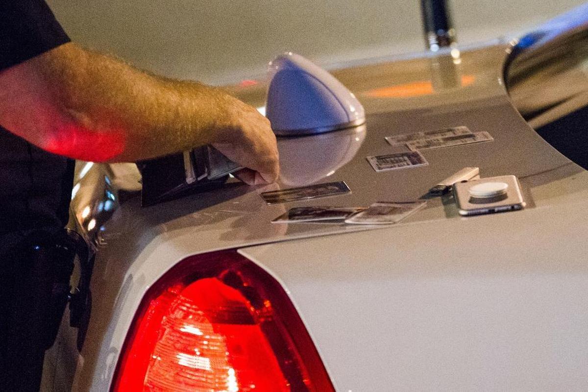 A Columbia Police Department officer examines various IDs found in the wallet of a man they placed in their car.