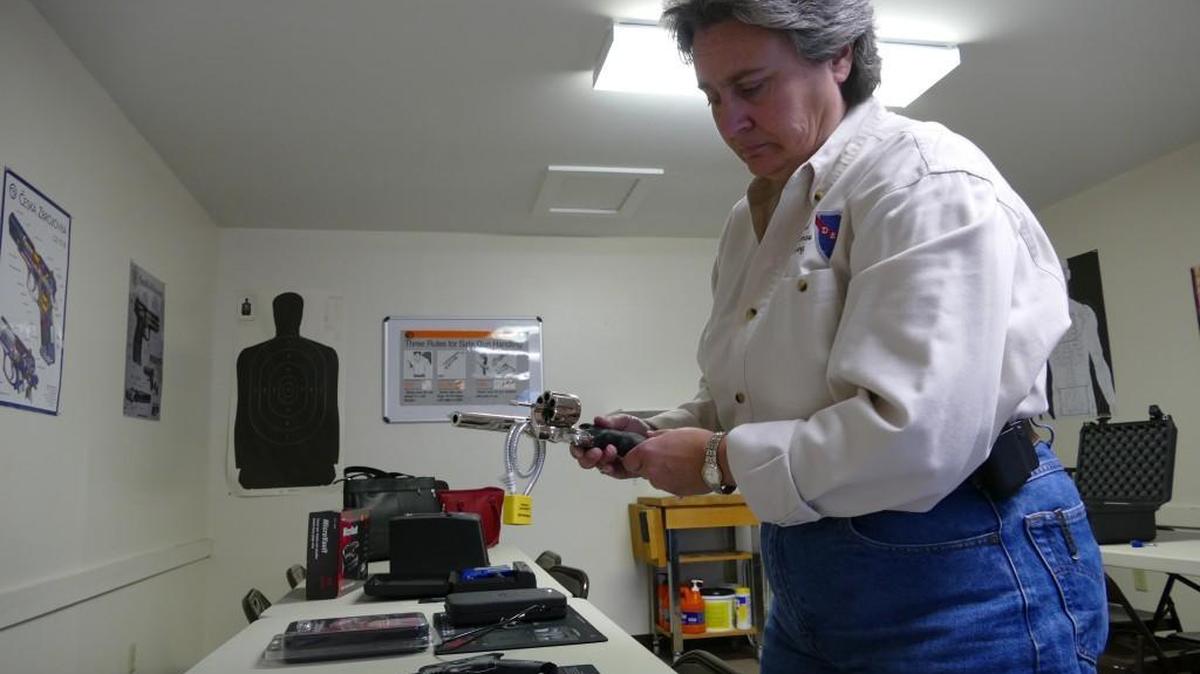 
DES Training owner Elizabeth Saunders demonstrates how to engage a cable lock on a revolver. Saunders teaches gun owners about various safety measures including putting weapons in a safe. 
