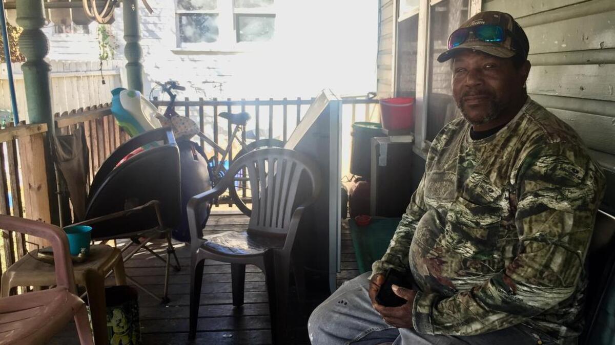 Charles Hill sits on the front porch of his Rosewood home, where he and his wife, Evelyn, spend many days with friends. Letters spreading rumors about the Hills have been sent to some of their neighbors.