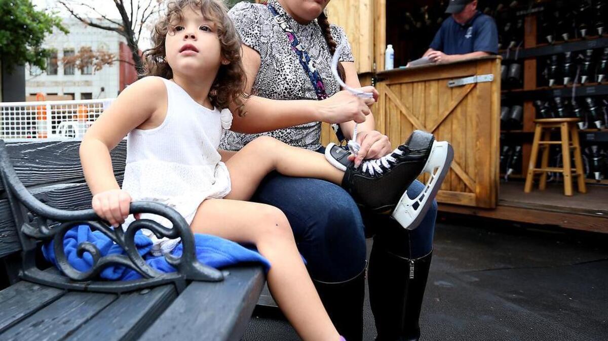 Jill Messer ties up an ice skate for her daughter, Anna Grace, on an unusually warm December day at Main Street Ice. Tempertures are expected to reach the 80s on Christmas day.