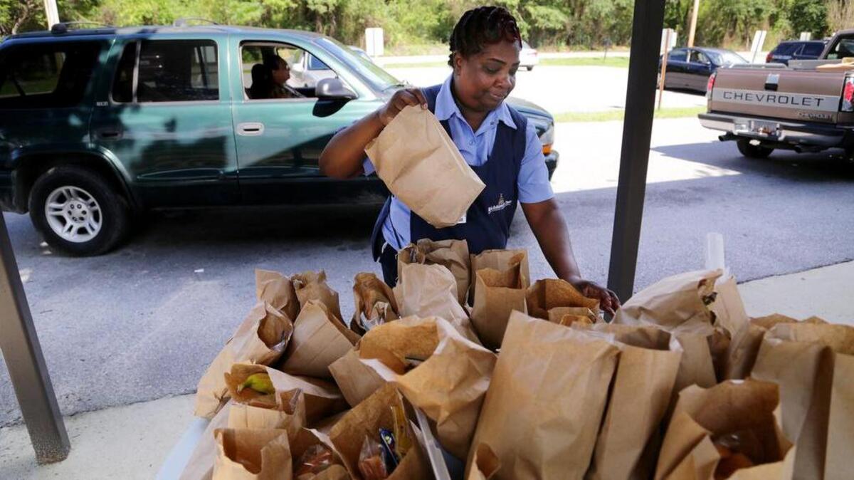 
Valerie Capers helps distribute bag lunches to Lower Richland County residents as they pull up for supplies, water and food at Gadsden Elementary School, Monday, October 12, 2015.
