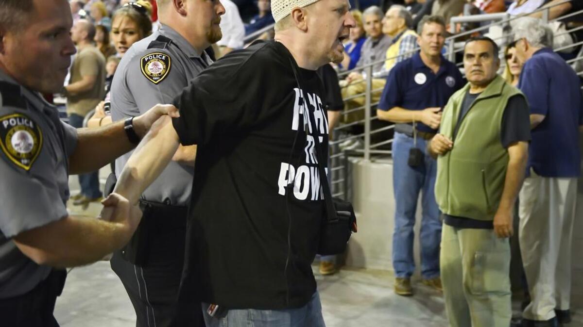 Charlotte’s Jibril Hough is escorted out while Republican presidential candidate Donald Trump speaks Saturday at a town hall meeting in the Convocation Center on the University of South Carolina Aiken campus.