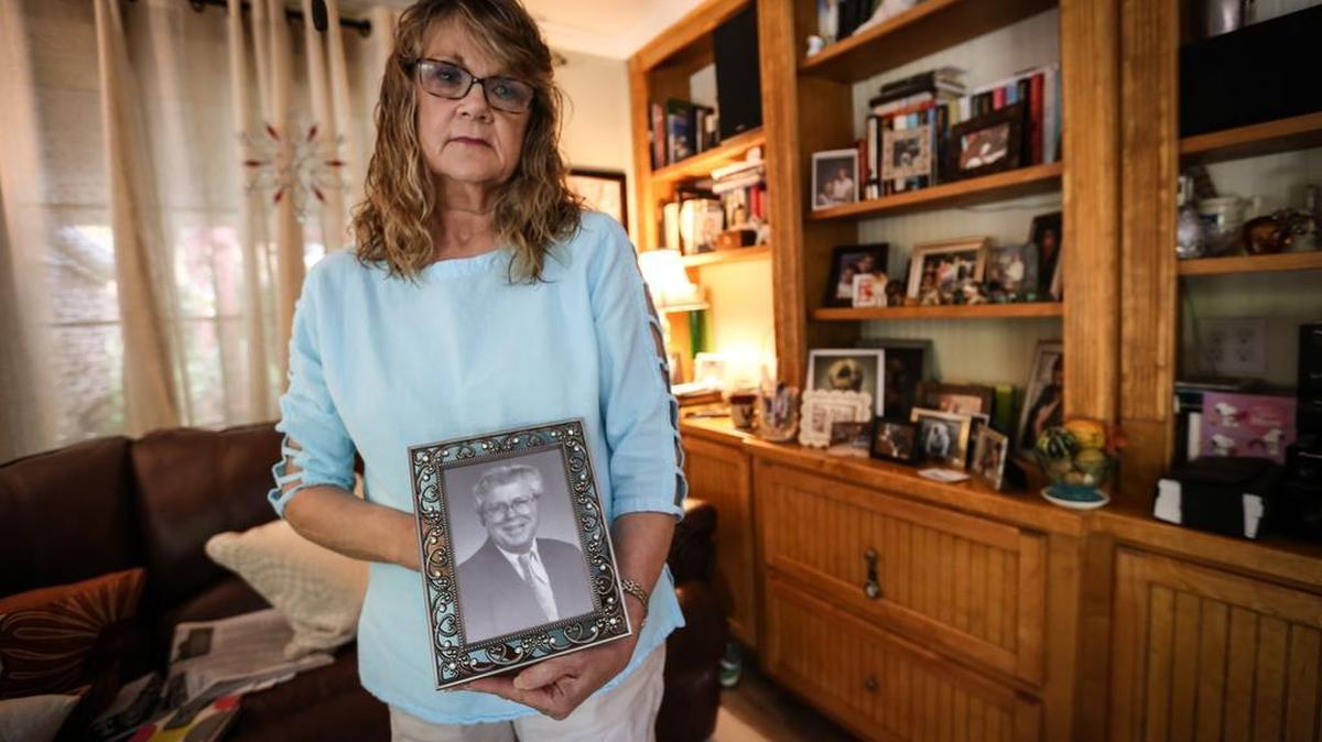 Lois McCarty holds a photo of her husband, Bob, who died in the October flood. Lois thinks the failure of the Semmes Lake dam on Fort Jackson contributed to her husband's death.