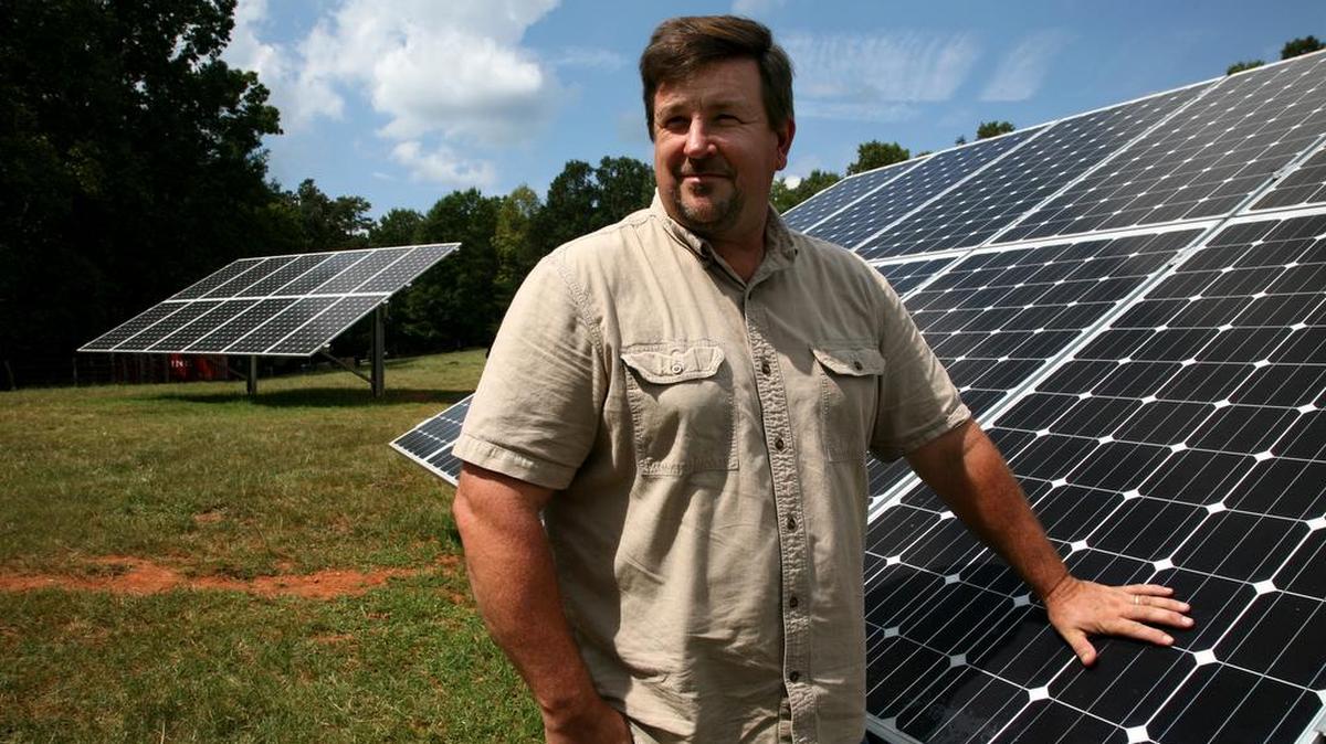 Scott Hunt, on his farm in Pickens. These are two of several solar panels that supply the energy to run his farm.