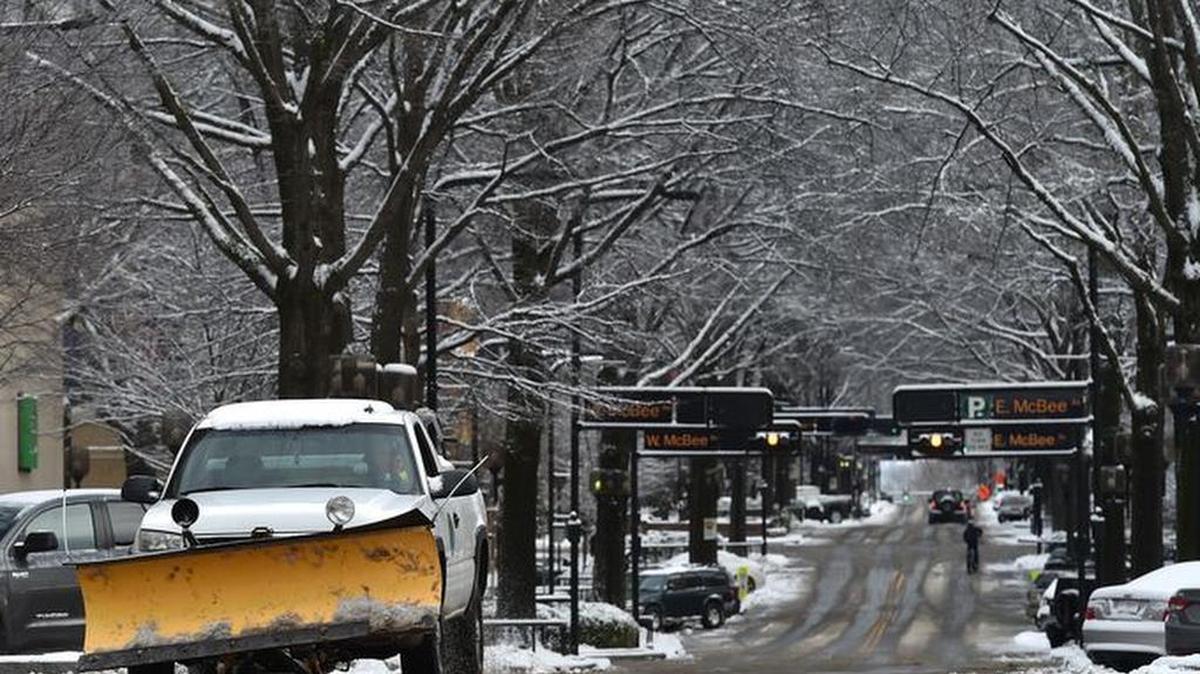 City crews clean snow off Main Street in downtown Greenville on Saturday.