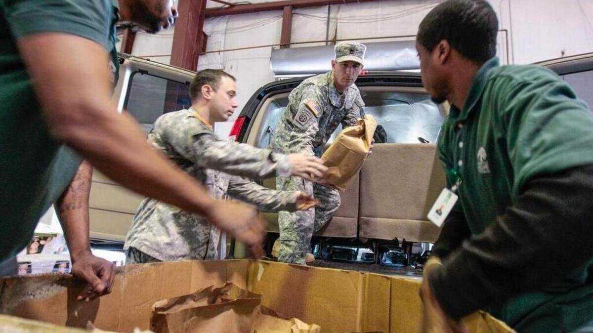 FILE PHOTO: Harvest Hope Food Bank volunteers gather food for a long line of people in need in 2013.