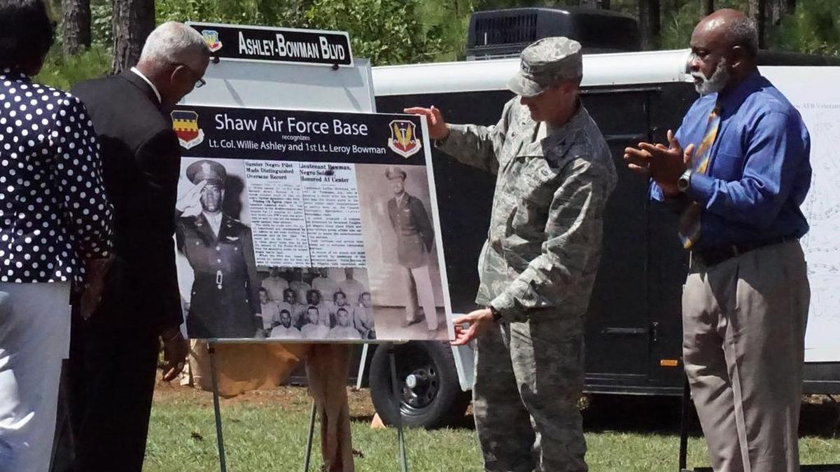 Retired Lt. Gen. George Bowman, left, son of Tuskegee Airman Leroy Bowman, and Shaw Air Force Base Commander Col. Stephen Jost, center, unveils a display about Leroy Bowman and Willie Ashley, two Tuskegee Airmen who are being honored at a street naming ceremony on Shaw Air Force Base on Thursday, as other dignitaries and family members, including Leroy Bowman's brother the Rev. Ralph Cantey, right, look on.