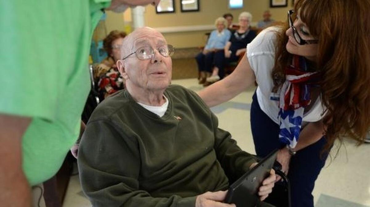 Deborah Hoopes, Lutheran Hospice Upstate Volunteer Manager, and Rick McKeeman, Lutheran Hospice volunteer and navy veteran, hand a certificate to George Irwin, center, during ceremony where Lutheran Hospice Upstate honored veterans at Rolling Green Village. The veterans received a certificate of appreciation and an American flag pin.