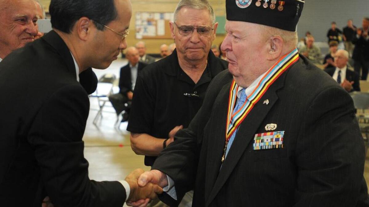 Lee Ayers, 84, of Greenville, receives the Ambassador of Peace medal from South Korea deputy consul general Sangho Lee.
