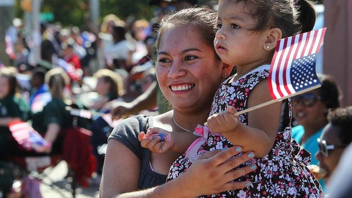 Carla Gonzales and her daughter Amaya, 19 months, wait for her sister to march by in the City of Columbia's 36th Annual Veterans Day Parade. November 11, 2014.