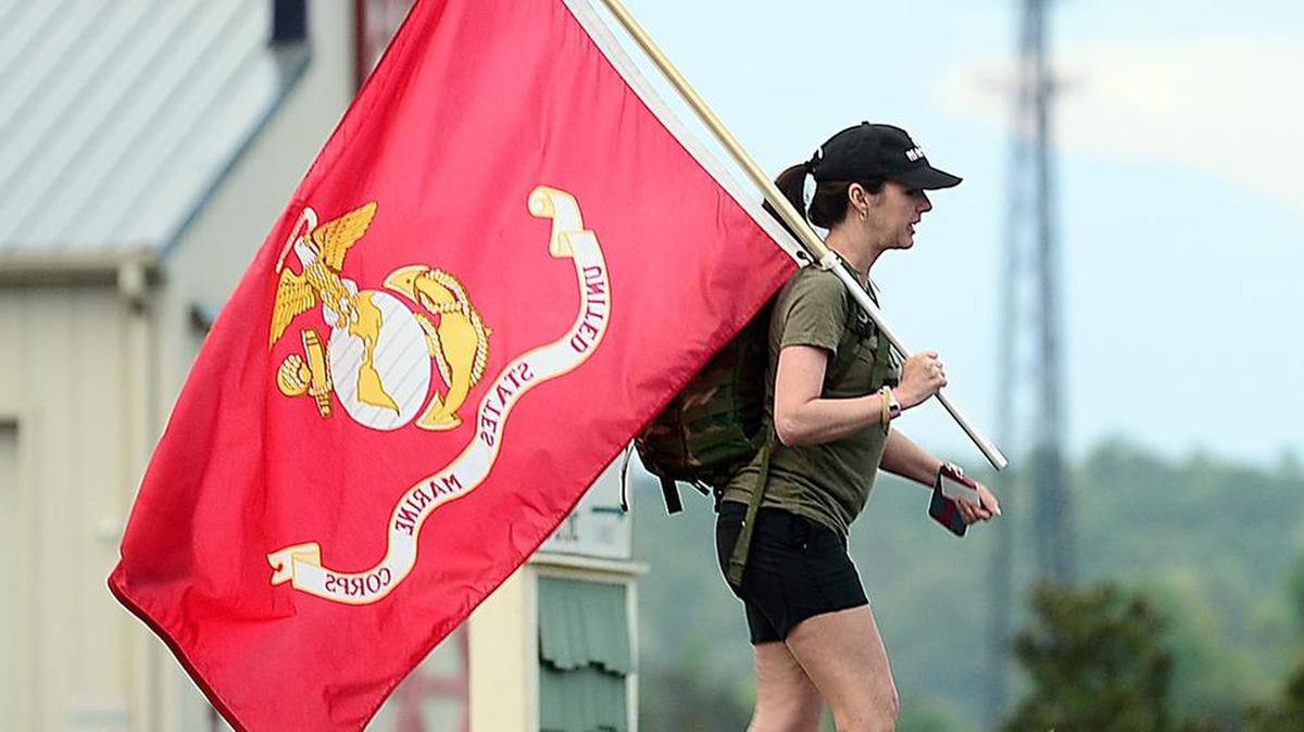 Renee Nardone, wife of David Nardone a retired Marine from Greenville, carries a Marine Corps flag behind a group of veterans who walked 22.2 miles from Landrum to Greer to shine light on the suicide rates among veterans.