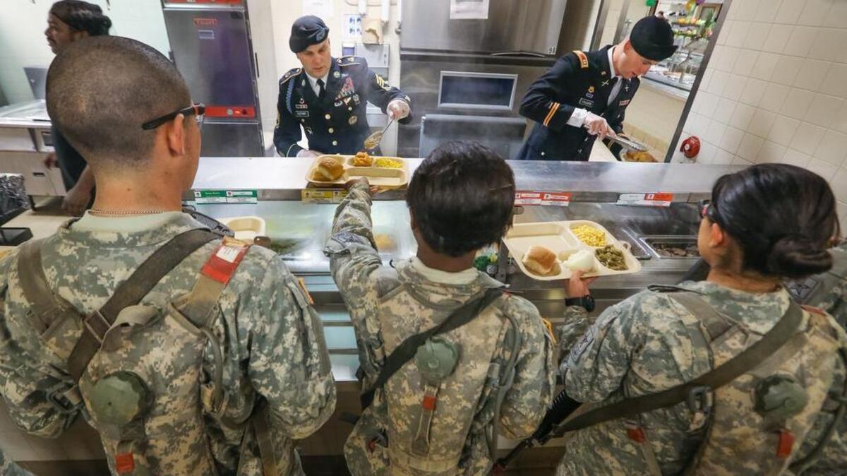 1st Sgt. Mike Fletcher, left, and Capt. Samuel Vaughn, right, dish up food to soldiers of the 1st Battalion, 13th Infantry Regiment during their Thanksgiving meal at Fort Jackson Wednesday.