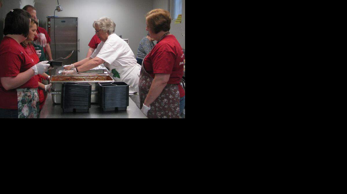 
 Bank of America volunteers put hot food in trays to be sealed and delivered to Meals on Wheels clients. 
