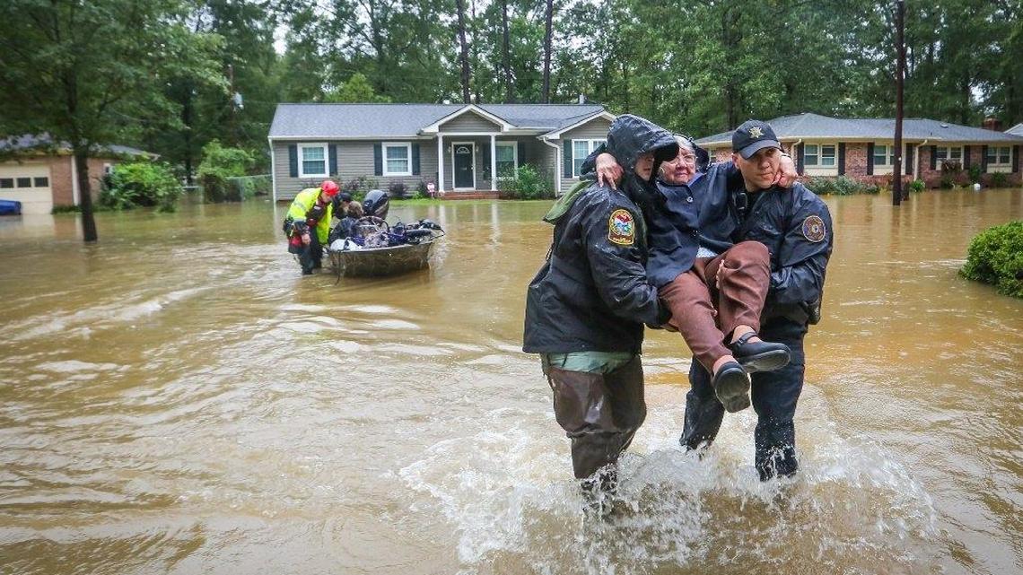 On October 5, 2015, DNR officer Brett Irvin and Lexington Co. Deputy Dan Rusinyak carry June Loch to dry land after she was rescued from her home in the Pine Glen subdivision off of Tram road in the St. Andrews area of Columbia.