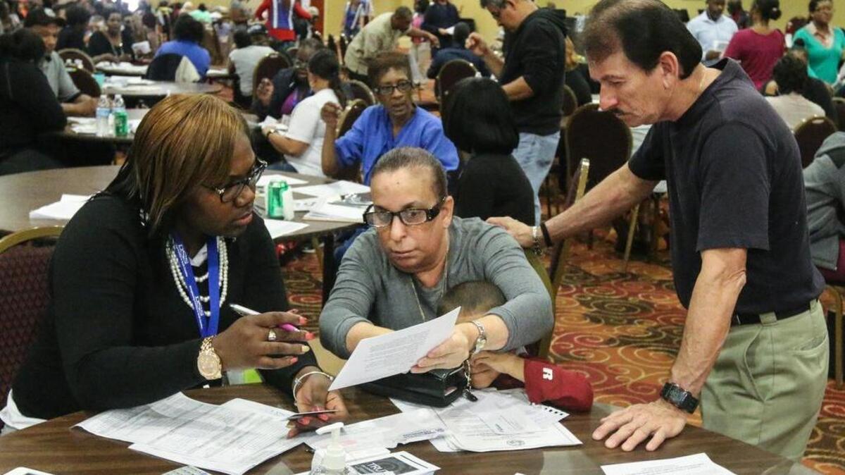 Tynice Hamilton, left, helps Maria Rosario and her husband, Miguel Vargas, apply for food assistance at a processing center at The Word of God Church and Ministries.