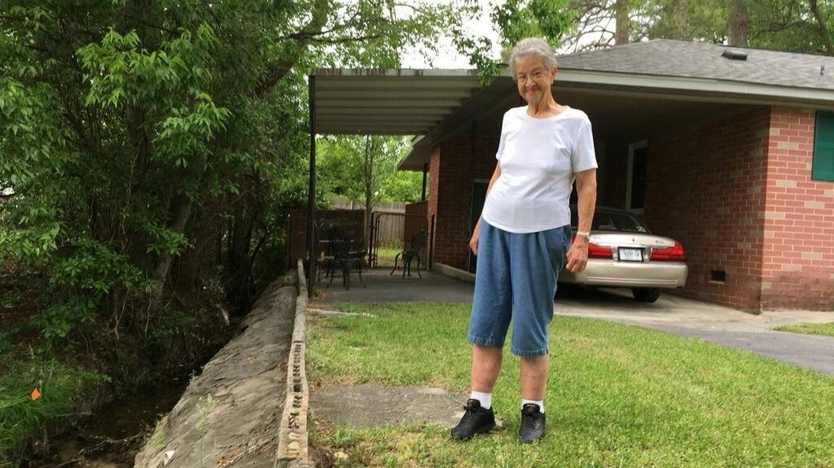 Jackie Weaver checks on the concrete wall in a ditch next to her home.