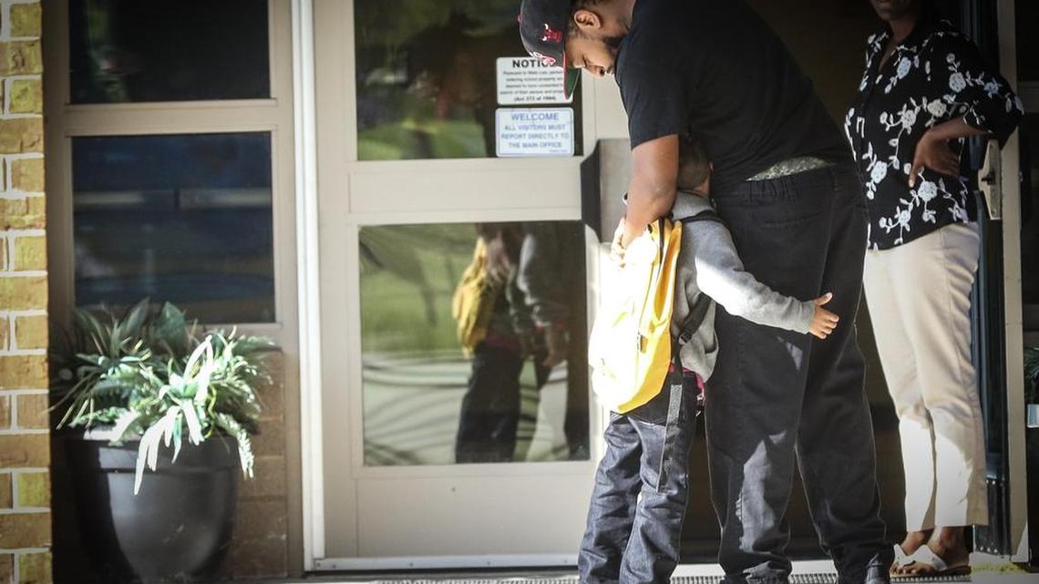 Antwan Lindsay hugs his son Tyree before schoool at Polo Road Elementary School on the first day of class after last weeks rainstorm that caused flooding across the state . The school modified routines to go on with classes without running water.