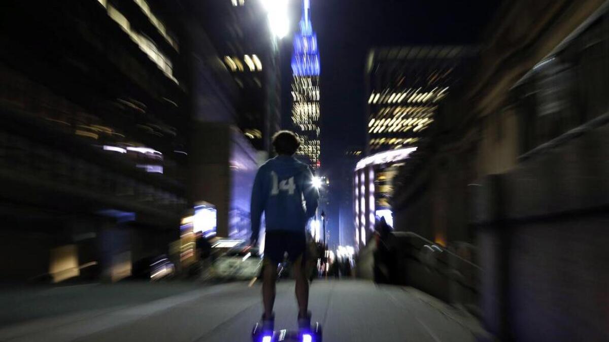 A young man rides a hoverboard along a Manhattan street toward the Empire State Building in New York in 2015. More than 500,000 hoverboards are being recalled after reports that they can burst into flames.