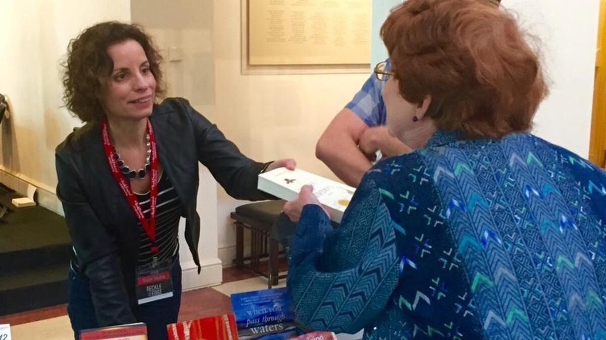 Author Susan Tekulve, of Spartanburg, hands a signed copy of her novel, “Garden of Stone,” to a customer after speaking on a panel as part of the Deckle Edge Literary Festival.