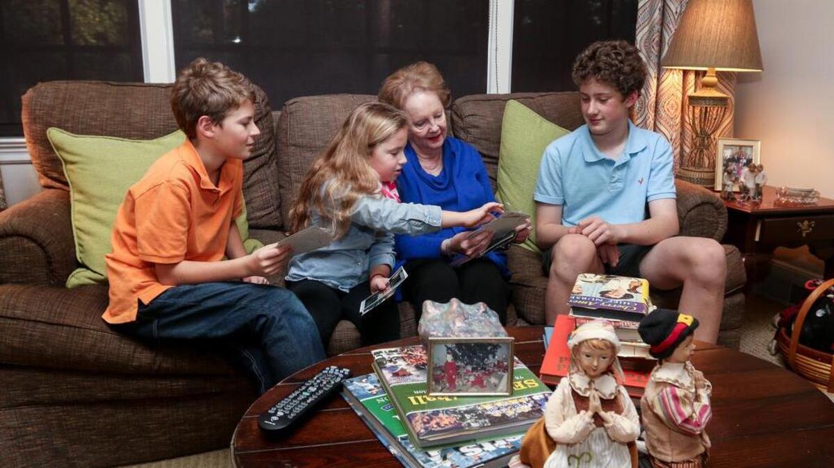 Ann Kepley was displaced from her house during the floods. This Thanksgiving her family will be hosting her for the annual meal that she traditionally prepared for them. Here Kepley shares family photographs salvaged from the flood with her grandchildren, from left, Will Kepley, 12, Grace Kepley, 12 and Tommy Kepley, 13.