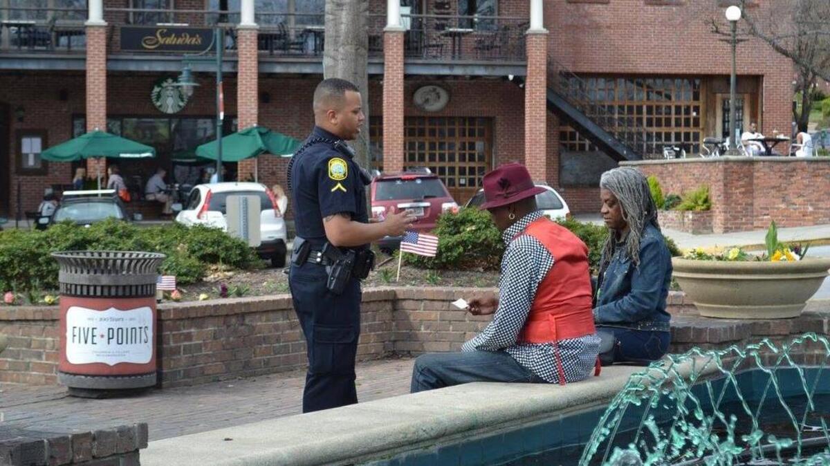 A Columbia police officer hands out a new text message survey card to citizens in Five Points.
