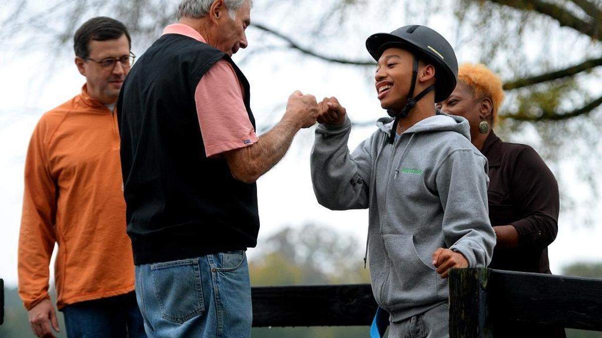Chancellor Lee Adams, right, fist bumps Harry Swimmer prior to riding Raiderat Misty Meadows Farm in Weddington, N.C. Chancellor participates in the therapeutic horse riding program there. .