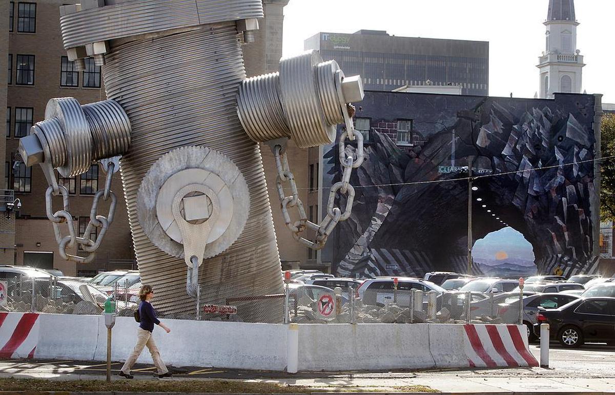 The Busted Plug sculpture, where it sat on Taylor Street before the property was sold for development and the 40-foot fire hydrant was donated to the city of Columbia. In the back is “Tunnelvision,” the mural on the Agfirst building also created by the Busted Plug artist, Blue Sky.