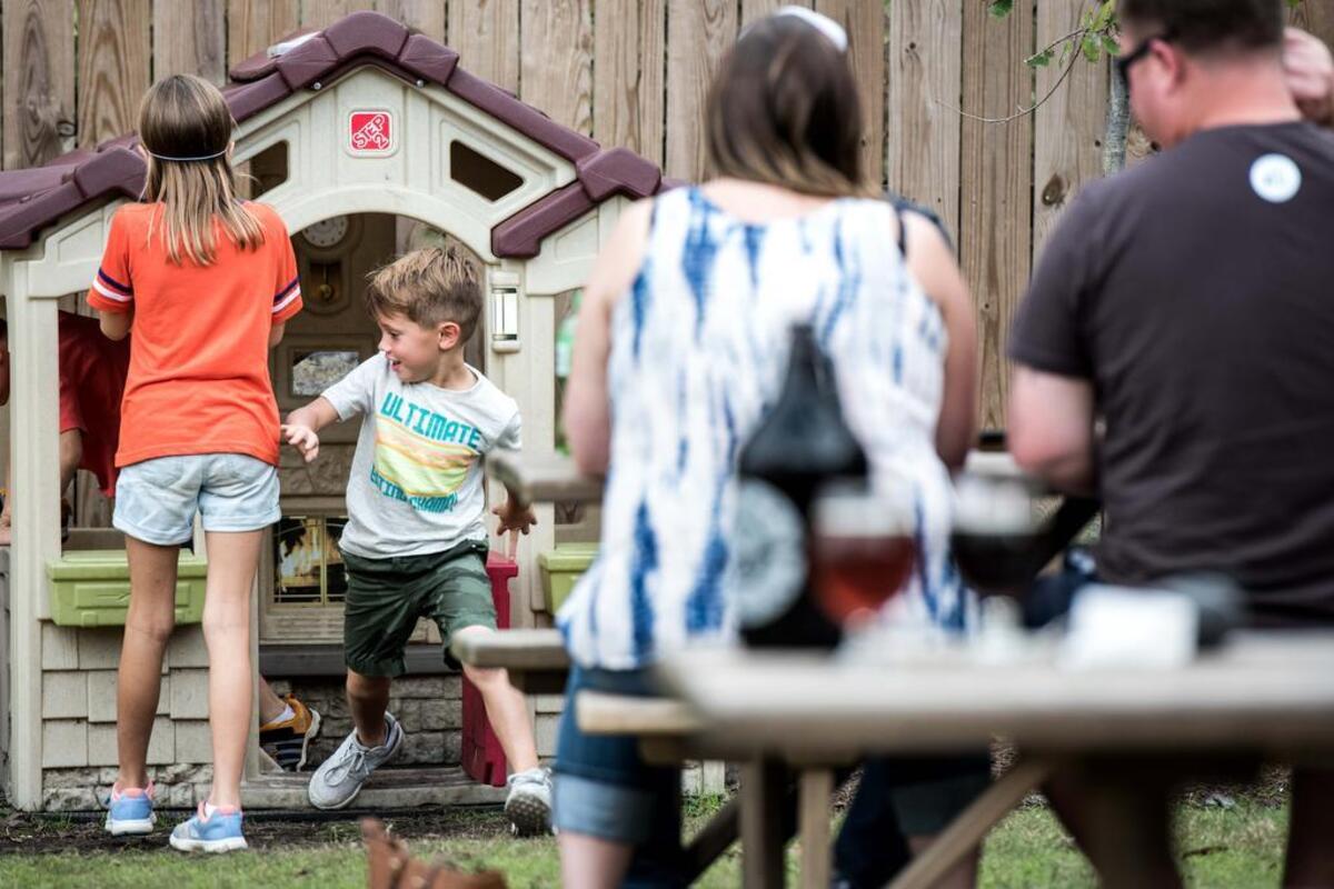 Children play outside at River Rat Brewery while their parents look on.