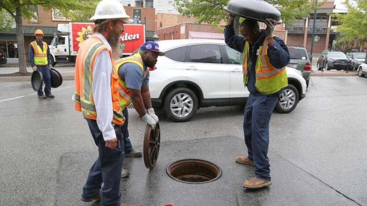 City of Columbia wastewater division employees place covers over manholes in Five Points on Oct. 2 to redirect stormwater in preparation for the rainy weekend.