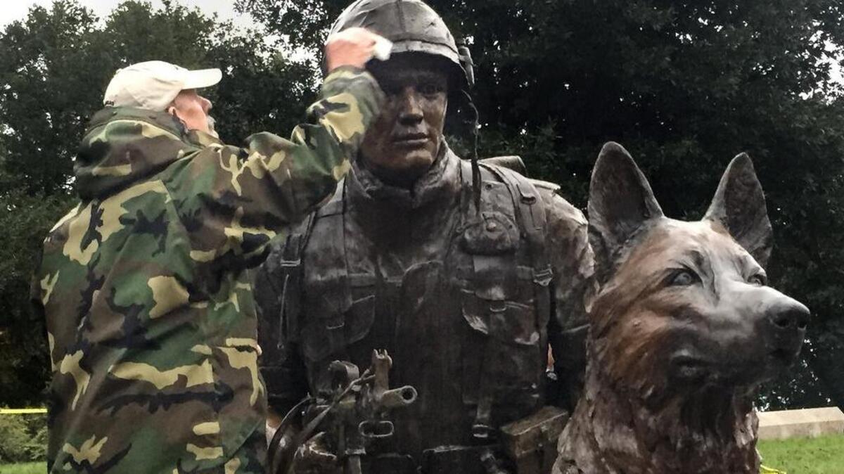 Veteran and war dog handler Johnny Mayo cleans the new war dog memorial at Columbia's Memorial Park. The monument to war dogs and their handlers will be dedicated during a ceremony on Veteran's Day.