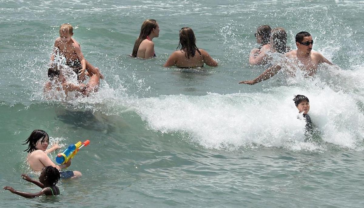 Swimmers crowd the waters at Wrightsville Beach, near Johnny Mercer pier.