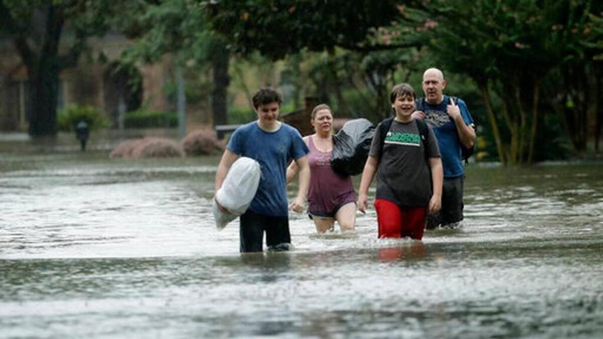 People evacuate a neighborhood inundated by floodwaters from Tropical Storm Harvey on Monday, Aug. 28, 2017, in Houston, Texas.