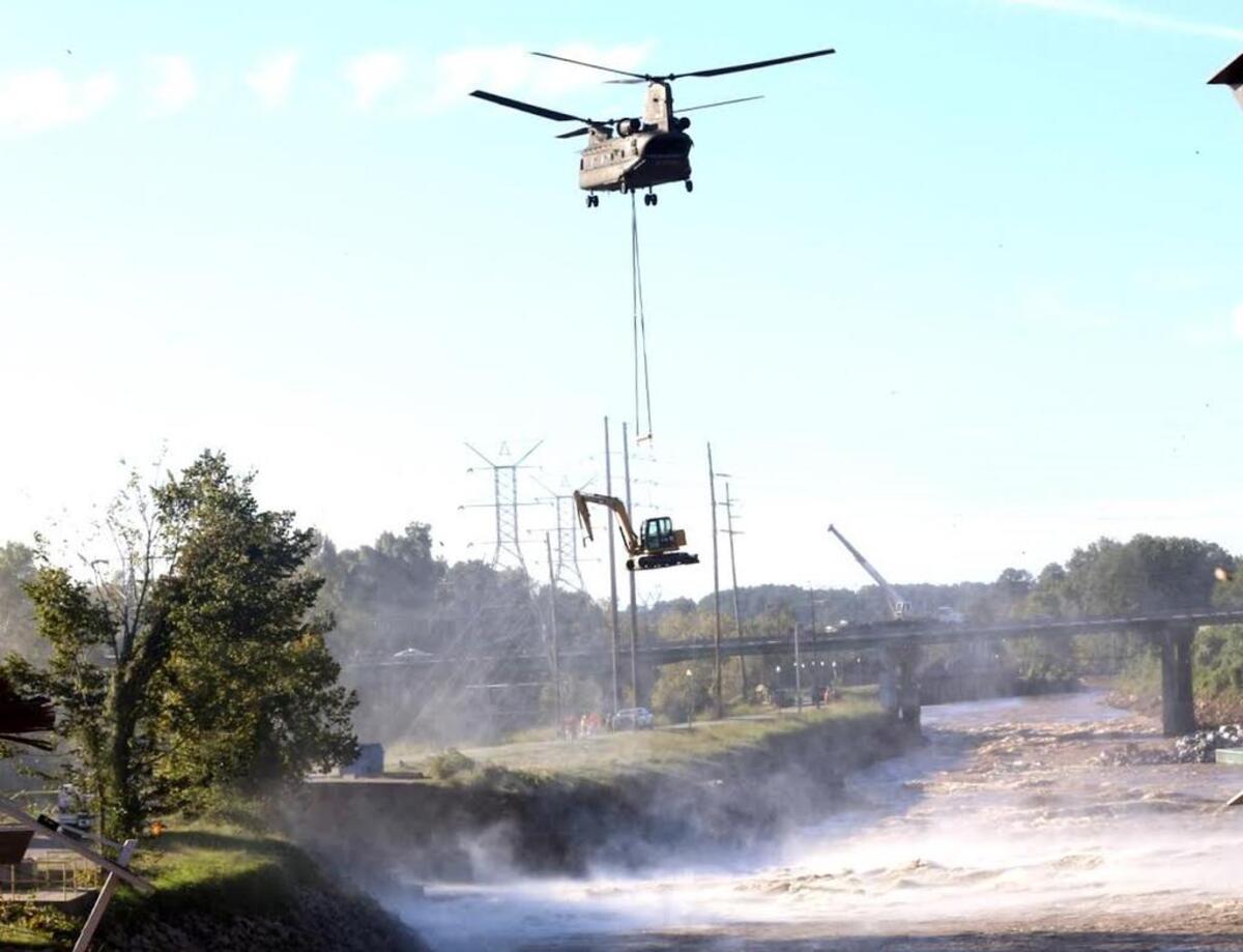 A Chinook helicopter from the S.C. National Guard hovers over the Columbia Canal Tuesday as it moves into position with equipment needed to repair a gashed dike.