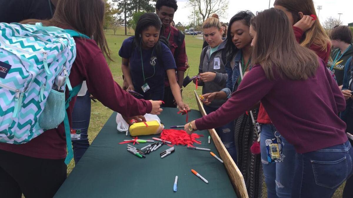 Spring Valley High School students reach for red ribbons during a pep rally Monday. Students will tie these to their cars during prom to show their commitment against drinking and driving.