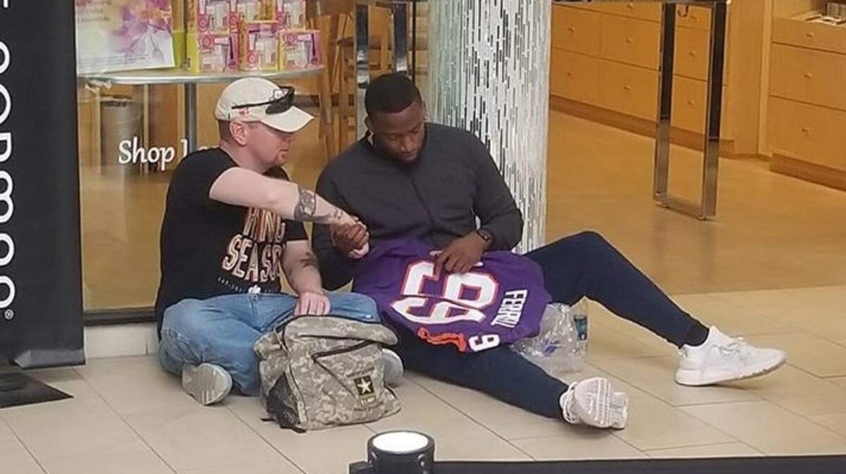 Clelin Ferrell, a former defensive end for the Clemson Tigers football team, is seen giving an autographed jersey to a military veteran at a Greenville autograph event for fans.